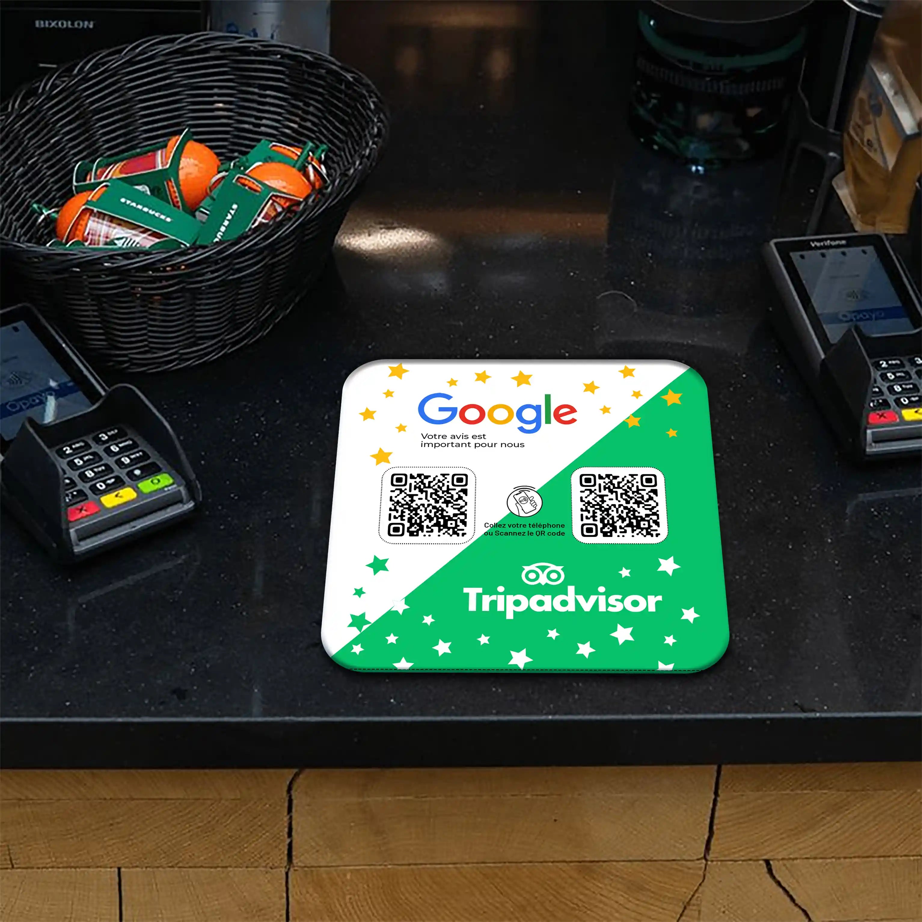 Plaque NFC et QR Code Google et TripAdvisor sur un comptoir de magasin avec des terminaux de paiement et un panier de chocolats.